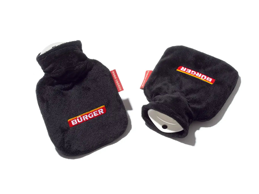 Zwei schwarze Wärmflaschen mit „BÜRGER“-Aufschrift und rotem „HUGO FROSCH“-Label auf weißem Grund.