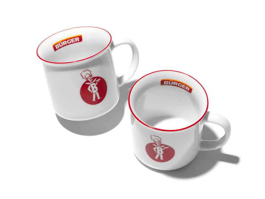 Zwei weiße Tassen mit rotem BÜRGER-Logo und Retro-Motiv, auf weißem Untergrund arrangiert.