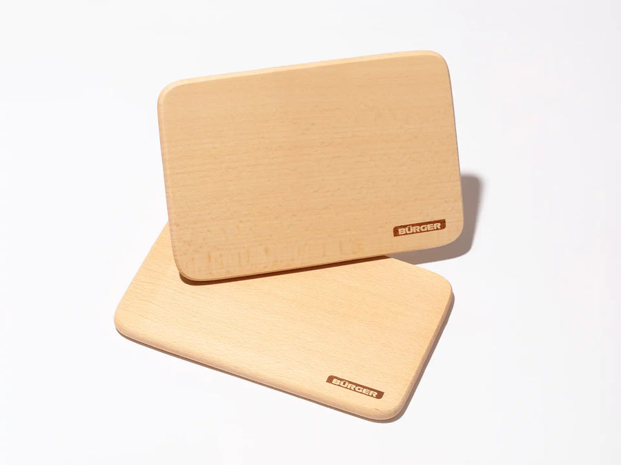 Zwei helle Holz-Schneidebretter mit eingraviertem BÜRGER-Logo auf weißem Untergrund.