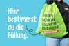 Grüner BÜRGER-Turnbeutel mit Aufdruck „Immer schön lecker bleiben!“ vor blauem Hintergrund.