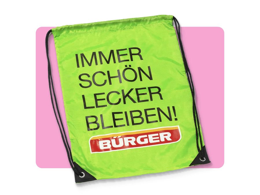 Grüner BÜRGER-Turnbeutel mit schwarzer Kordel und Aufdruck „Immer schön lecker bleiben!“