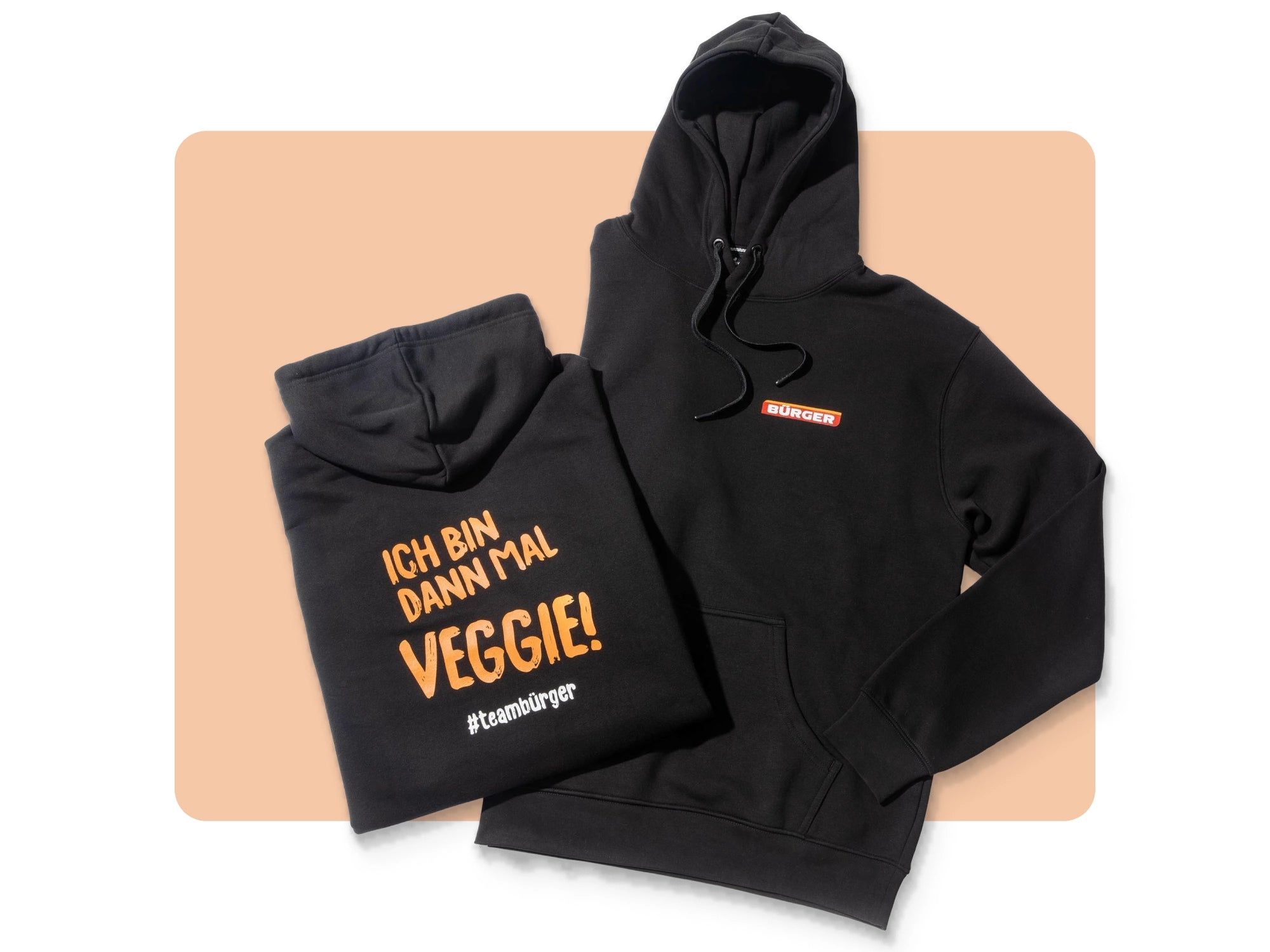 Zwei schwarze BÜRGER-Hoodies, einer mit Logo vorn, einer mit Rückendruck „Ich bin dann mal Veggie!“