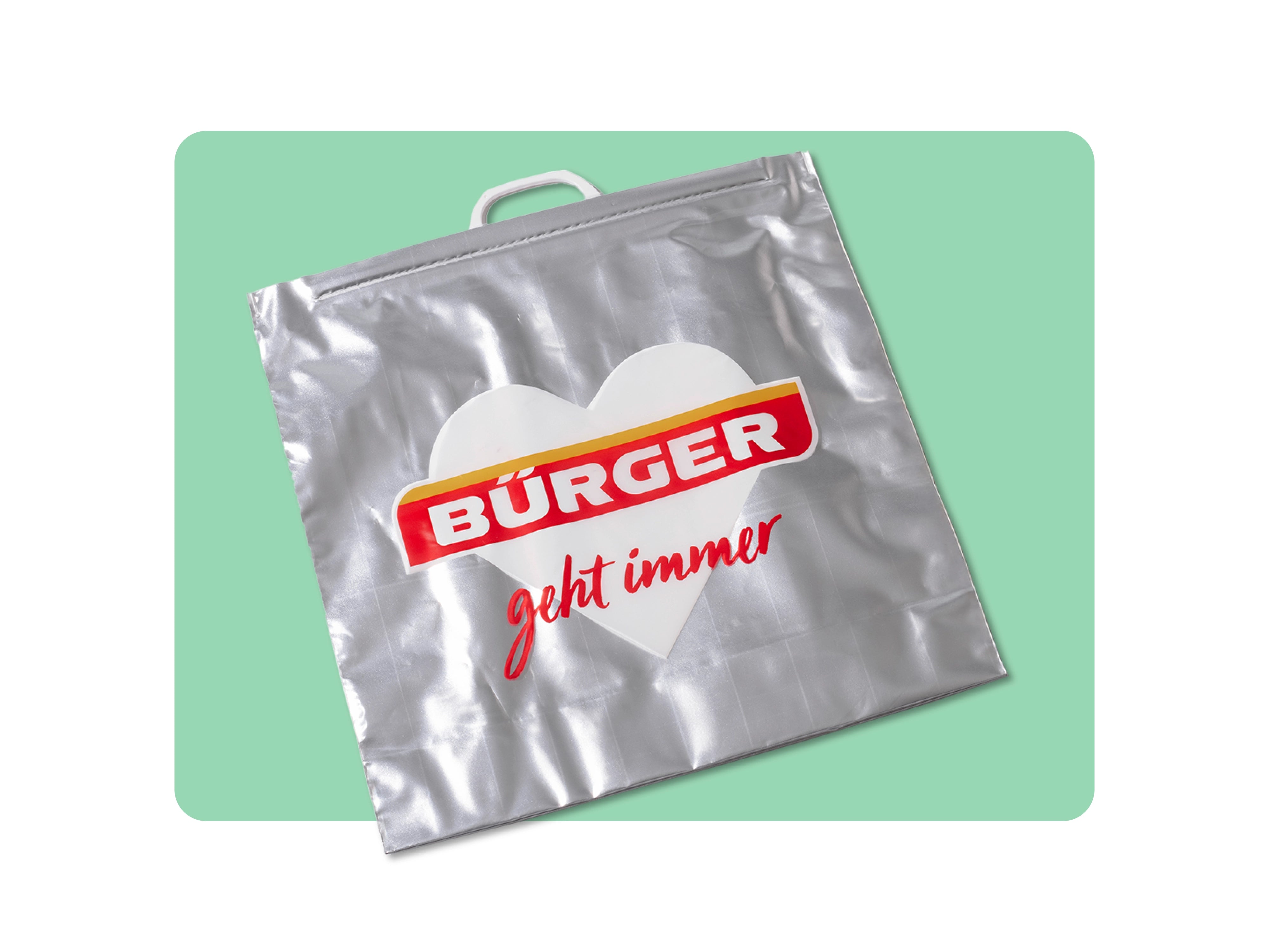 Silberne Tragetasche mit Herzmotiv, „BÜRGER“-Logo und rotem Schriftzug „geht immer“