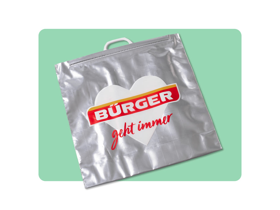 Silberne Tragetasche mit Herzmotiv, „BÜRGER“-Logo und rotem Schriftzug „geht immer“