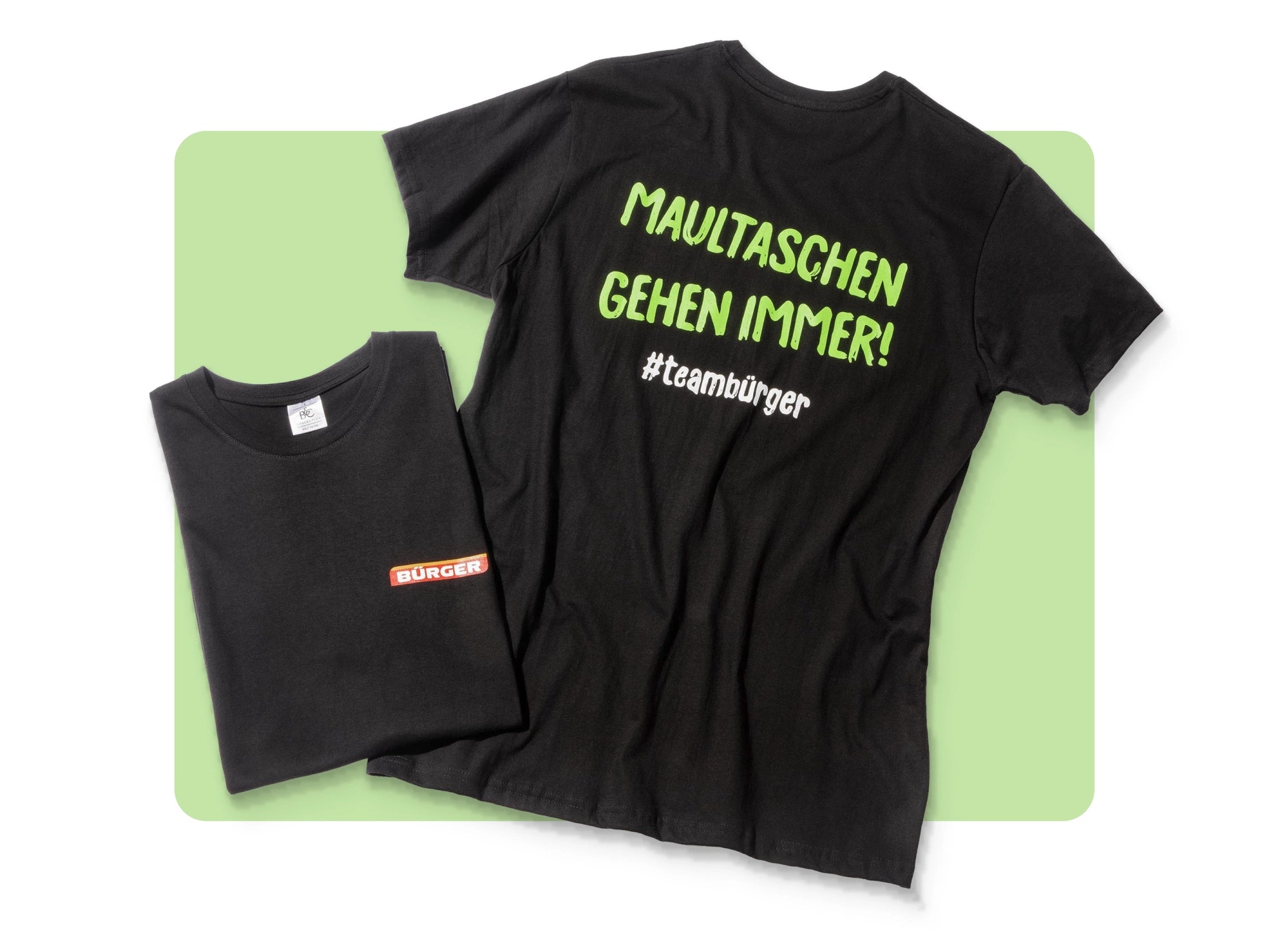 Zwei schwarze BÜRGER-T-Shirts, eines mit Spruch „Maultaschen gehen immer! #teamburger“.